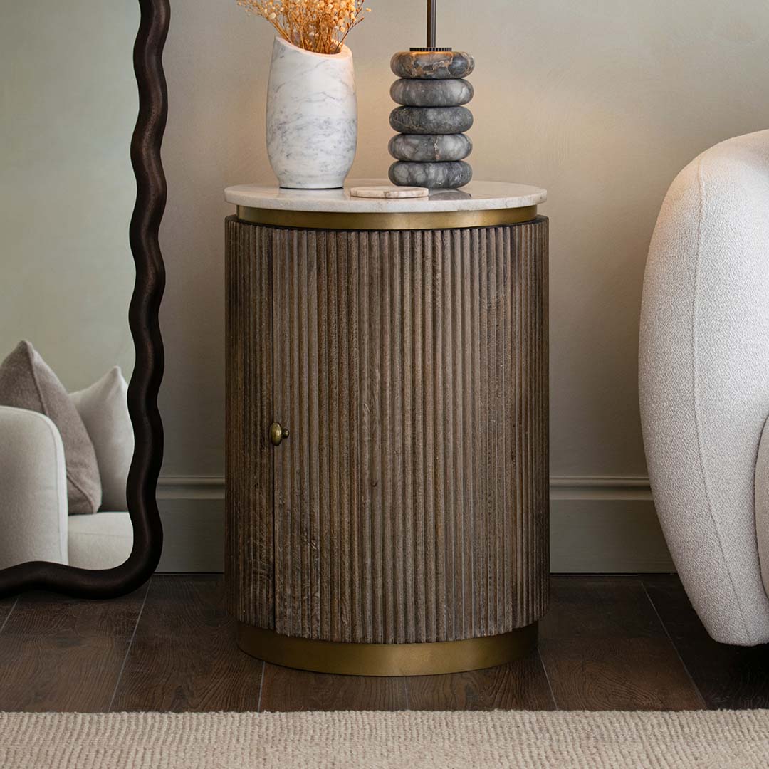 Round wooden side table with marble top in a room setting