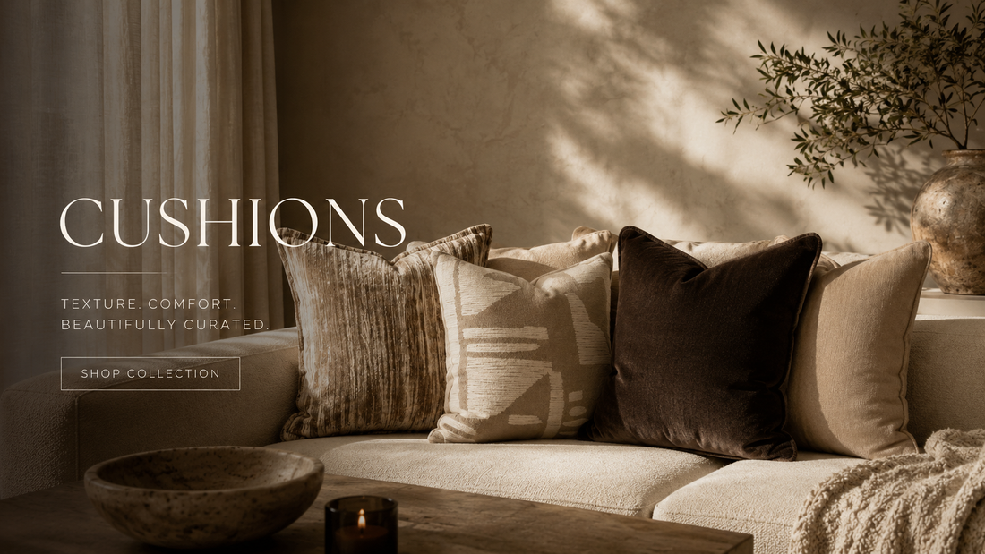 Layered neutral cushions in textured velvet, woven and bouclé on a warm sand-toned sofa with a chunky knit throw