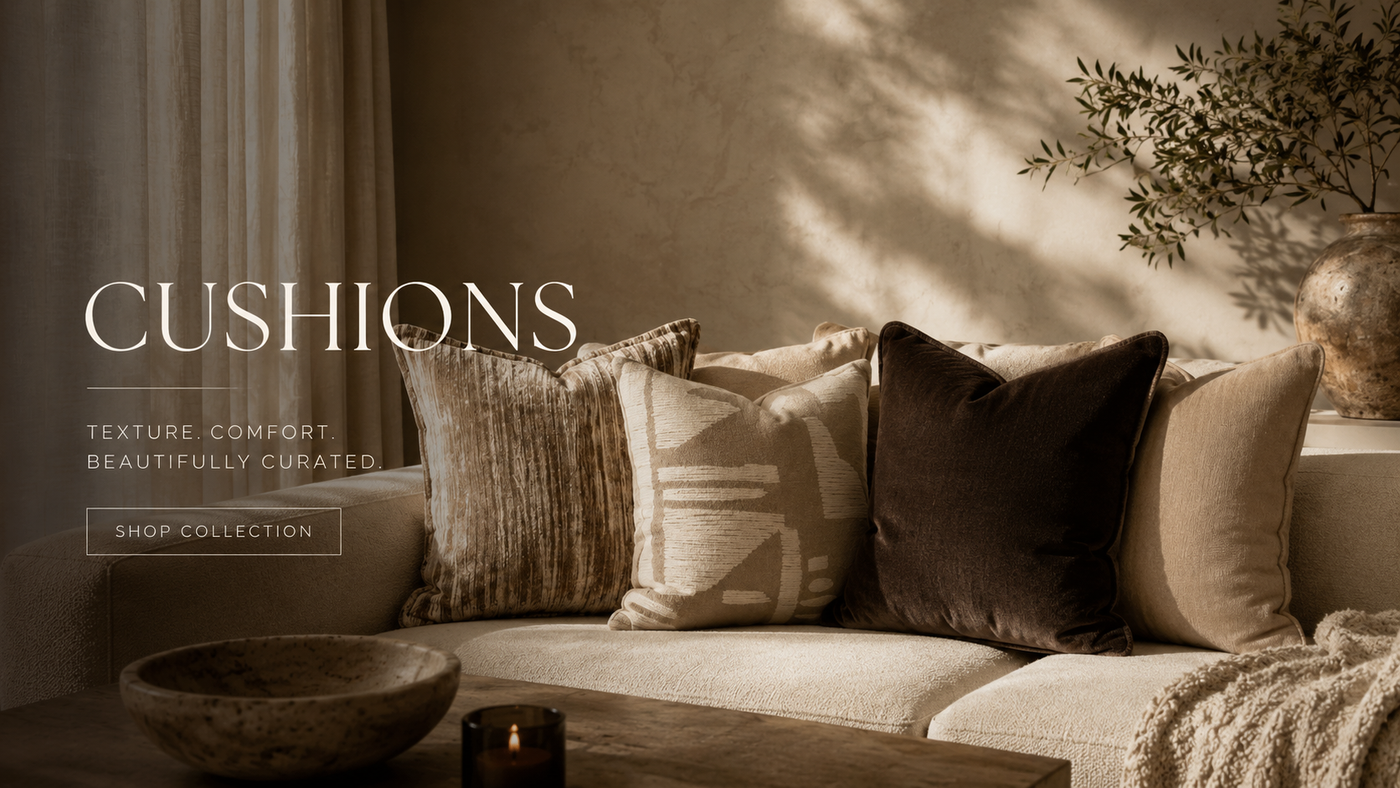 Layered neutral cushions in textured velvet, woven and bouclé on a warm sand-toned sofa with a chunky knit throw