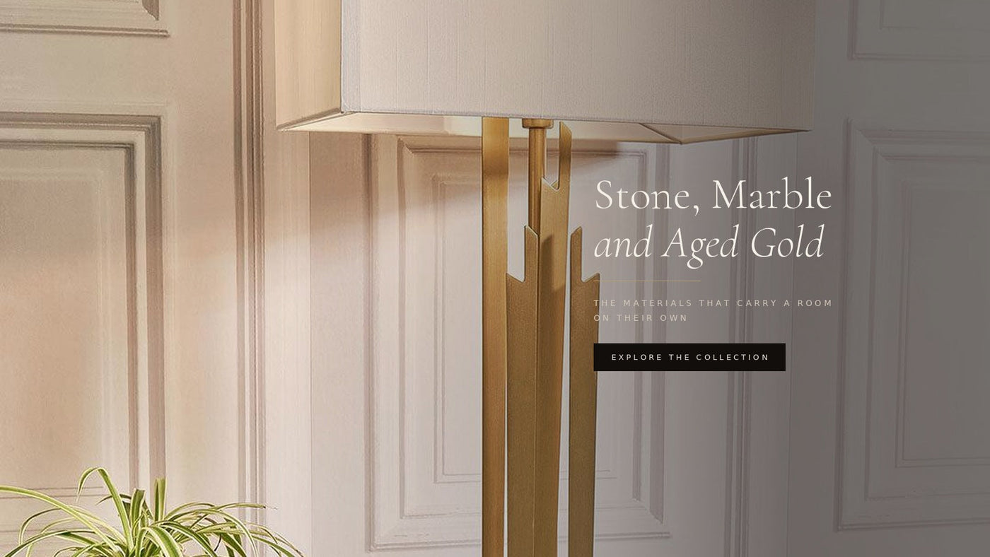 Antique brass Carrick table lamp lit against a panelled wall — Stone, Marble and Aged Gold