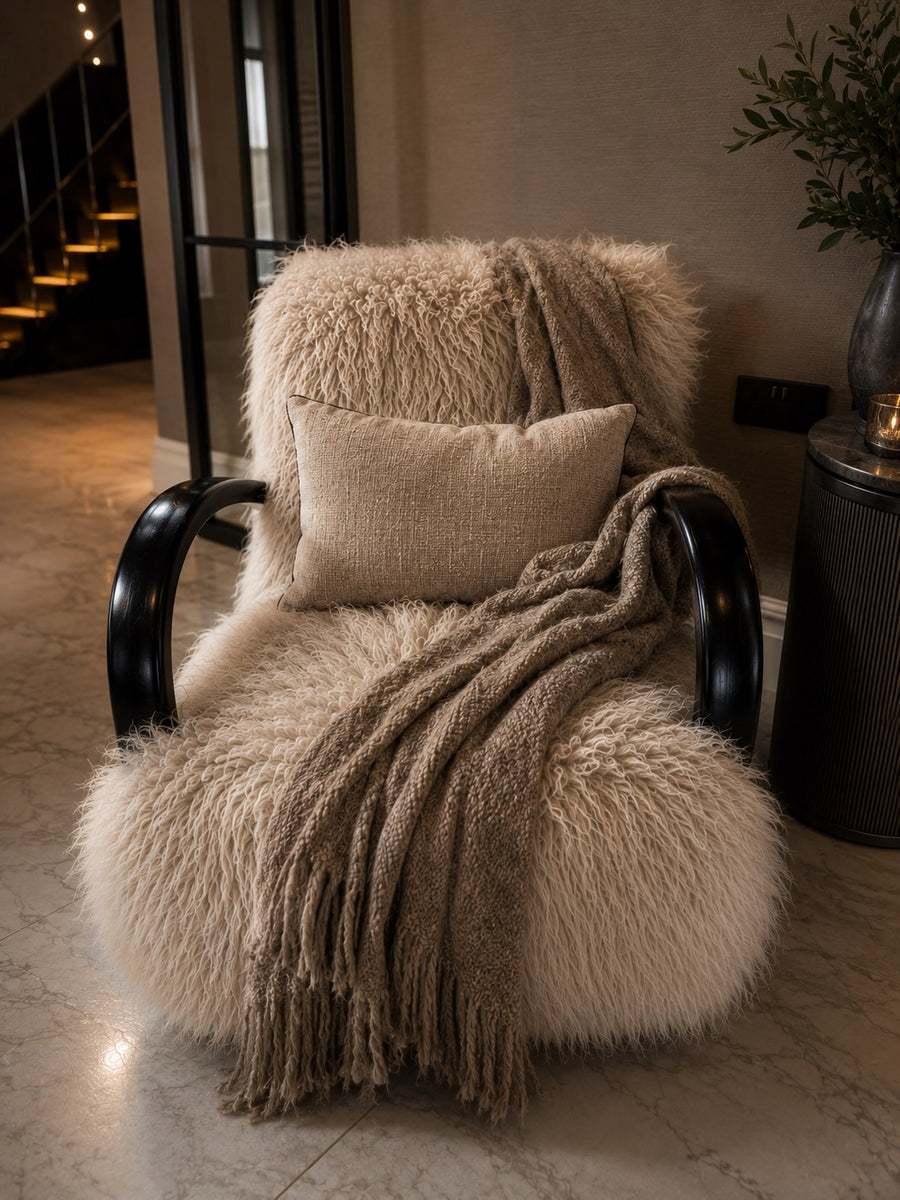 Textured cream armchair layered with cushions and a soft throw