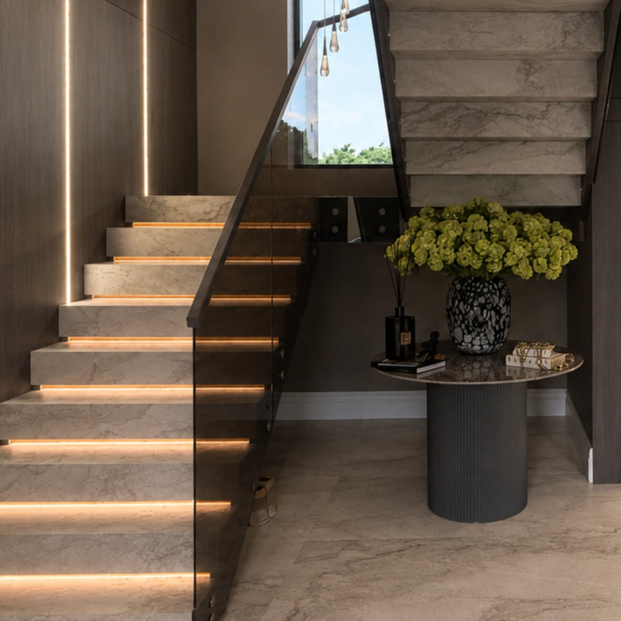 Illuminated staircase beside a console and floral arrangement